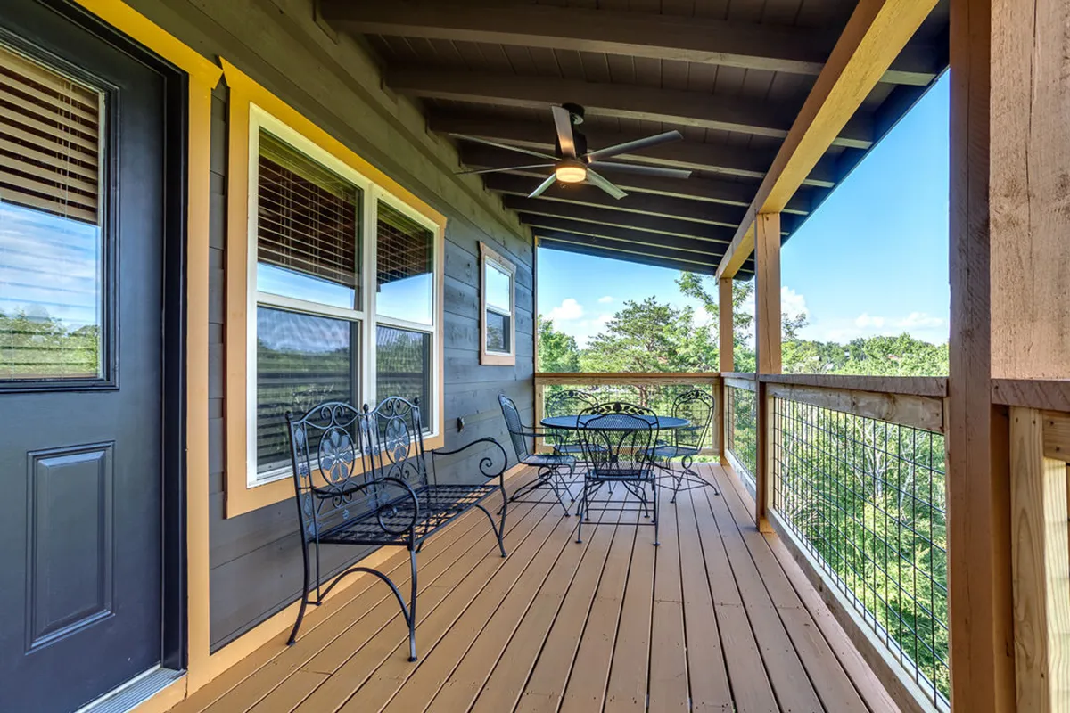 The outdoor dining area is set with metal chairs and a table on a deck with wooden railing, inviting guests to dine al fresco with a tranquil mountain backdrop.